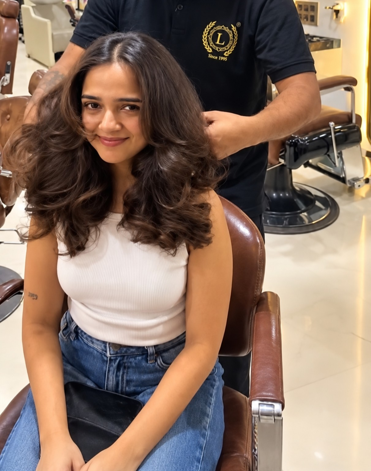 Woman with voluminous brown hair wearing a white top and blue jeans at Laséa Salon